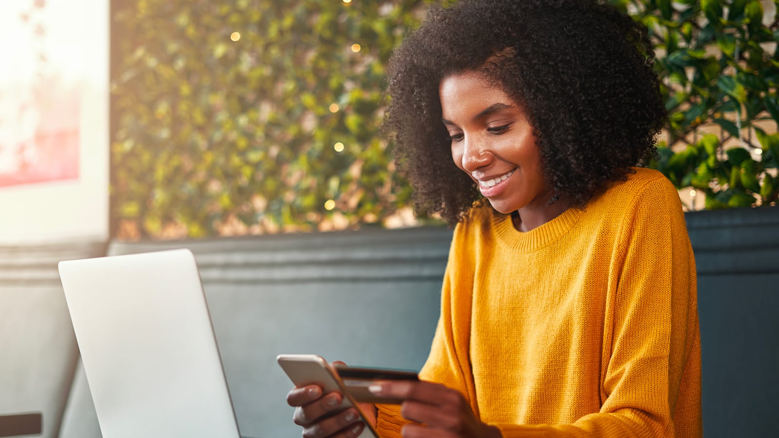 Young woman shopping online on mobile phone with credit card