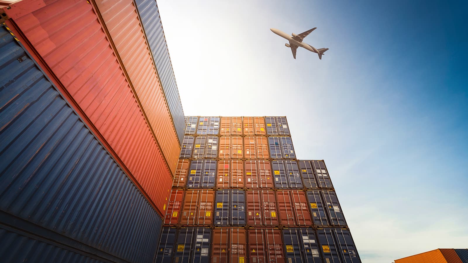 Airplane flying above container logistic