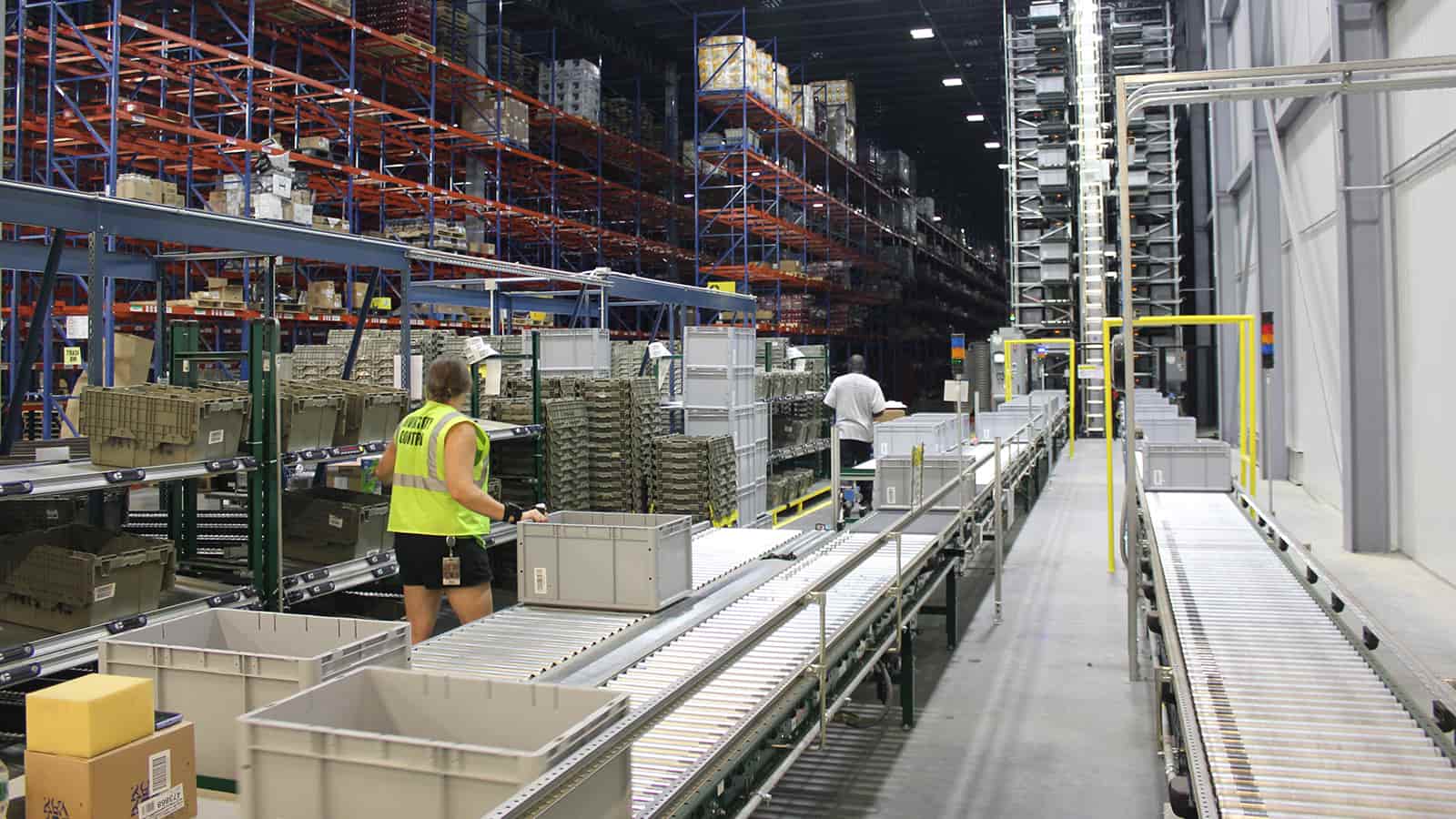 Workers in warehouse with racking and conveyor